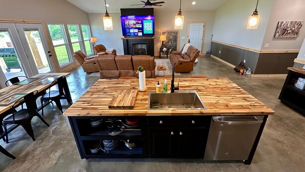 A spacious living room with a large wooden island, a flat-screen TV, and a fireplace.