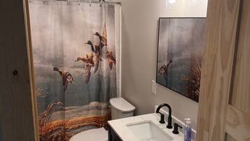 Une salle de bain équipée de toilettes, d’un lavabo et d’un rideau de douche orné d’un motif d’oiseau.