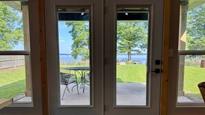 A double door with a view of a grassy yard and a lake.