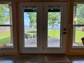 Une porte à deux battants donnant sur une cour verdoyante et un lac.
