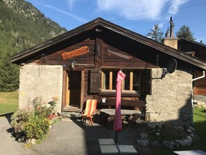 Une cabane rustique en bois, avec une façade en pierre, une véranda en bois et un banc.