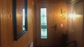 A wooden interior hallway with a door, a mirror, and a wall-mounted light fixture. - Lungern by Interhome (Bürglen OW)