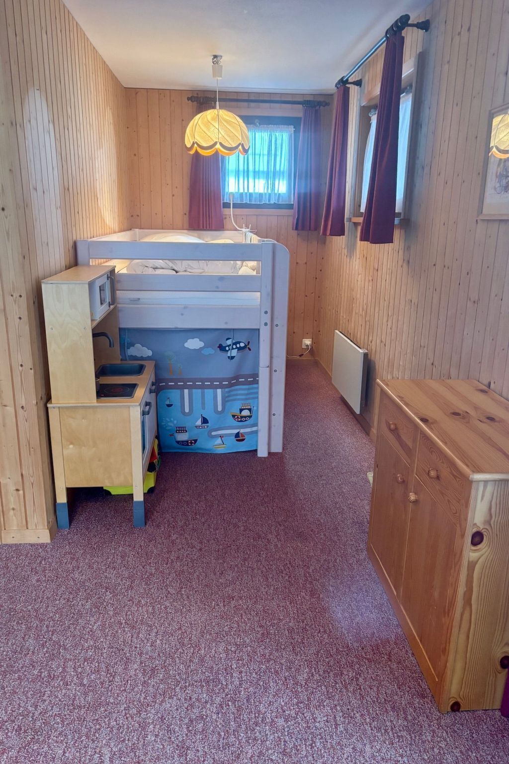 Une chambre d’enfant avec un lit superposé, un bureau et un espace de jeux.