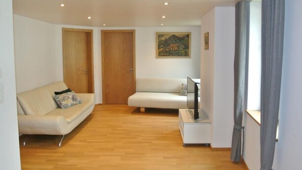 A modern living room with a sofa, a TV stand, and a painting on the wall. - Blaues Haus by Interhome (Appenzell)