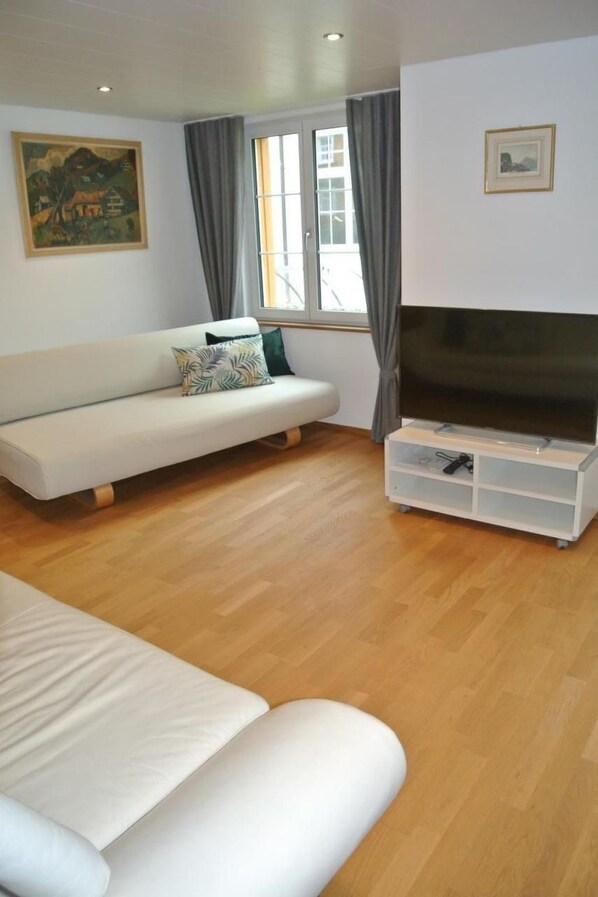 Un salon avec un canapé, un meuble pour la télévision et un tableau accroché au mur.