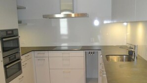 A modern kitchen with white cabinets, a stainless steel range hood, and a wooden floor. - Blaues Haus by Interhome (Appenzell)
