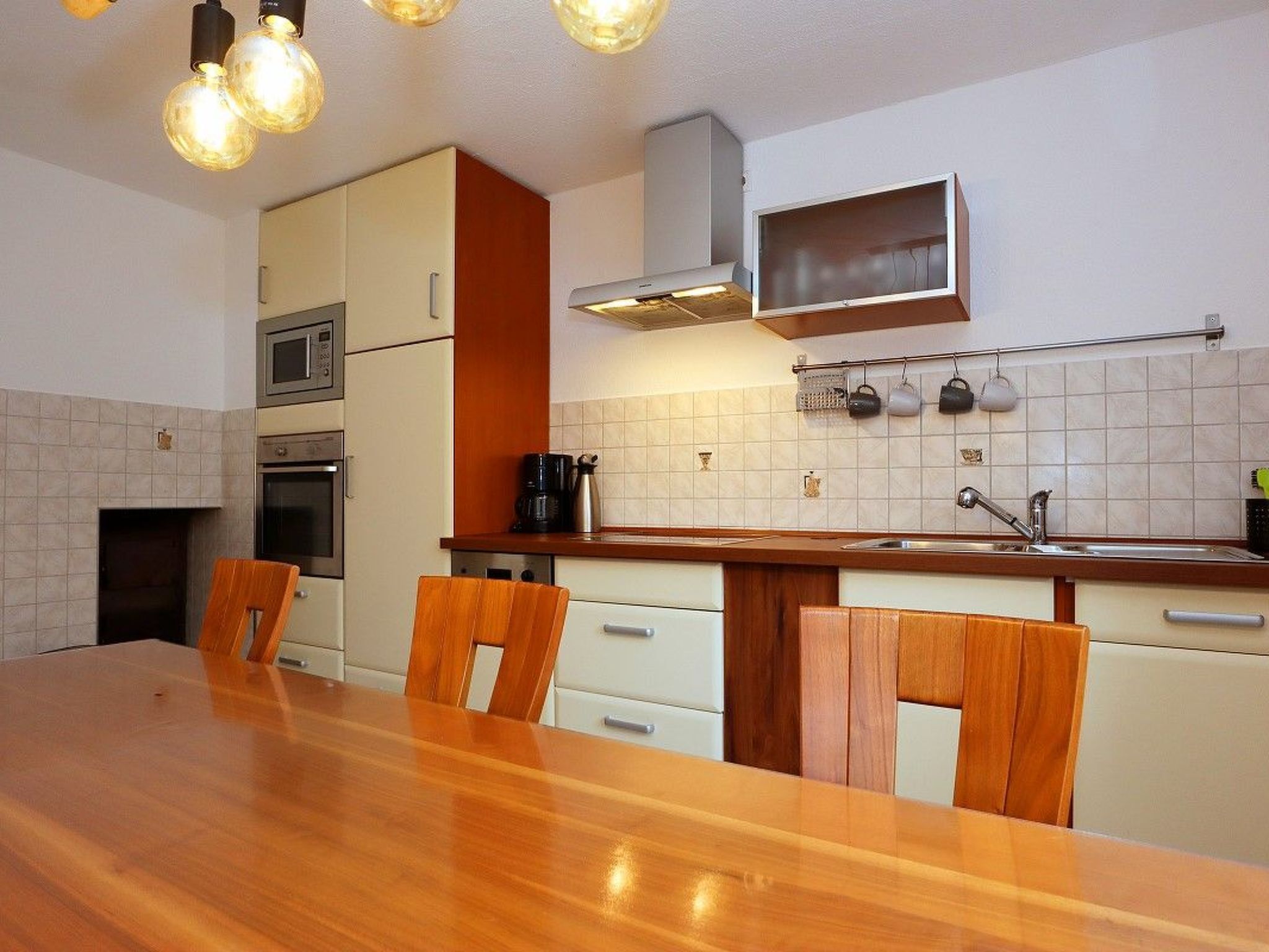 Une cuisine moderne avec une table à manger en bois, des placards blancs et un four à micro-ondes.