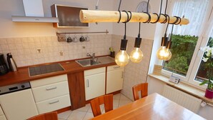 A modern kitchen with a wooden table, white cabinets, and a window with a view of greenery. - Bertsche 3 Schlafzimmer by Interhome (Rietheim)