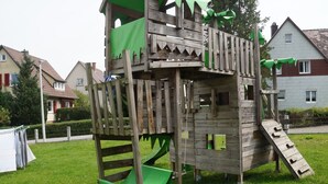 A wooden playground structure with a slide and climbing elements. - Bertsche 3 Schlafzimmer by Interhome (Rietheim)