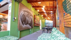 Ein gemütliches Zimmer mit grüner Wand, einem großen abstrakten Gemälde, einer Holzbalkendecke und einem grün gemusterten Sofa.