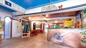 Ein Hostel-Innenraum mit Rezeption, einer Karte und einem Wandgemälde.