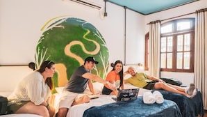 Ein Zimmer mit einer großen Wandmalerei, einem Bett mit einem Laptop und einem Fenster mit Vorhängen.