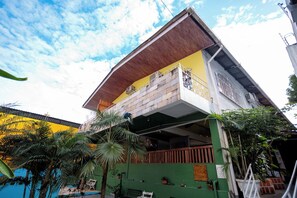 A multi-story building with a balcony on the upper floor, surrounded by greenery. - Local Hostel Manaus  (Manaus)