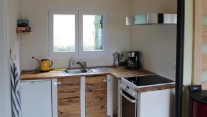 Una cucina compatta con un piano di lavoro in legno, un lavello, un fornello e una finestra sopra il lavello.