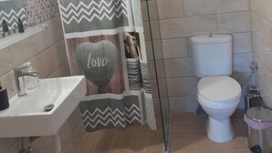 Casa de banho com cortina de chuveiro com o design 'Love', sanita e lavatório com espelho.
