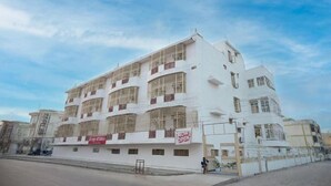 A multi-story building with balconies, a sign indicating it's open, and a clear sky. - Shri Thakur Ji Niketan Near ISKCON  (Vrindavan)