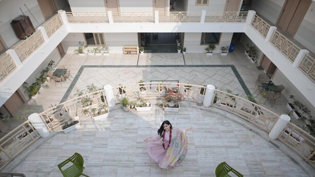 A spacious courtyard with a central seating area, surrounded by balconies and potted plants. - Shri Thakur Ji Niketan Near ISKCON  (Vrindavan)