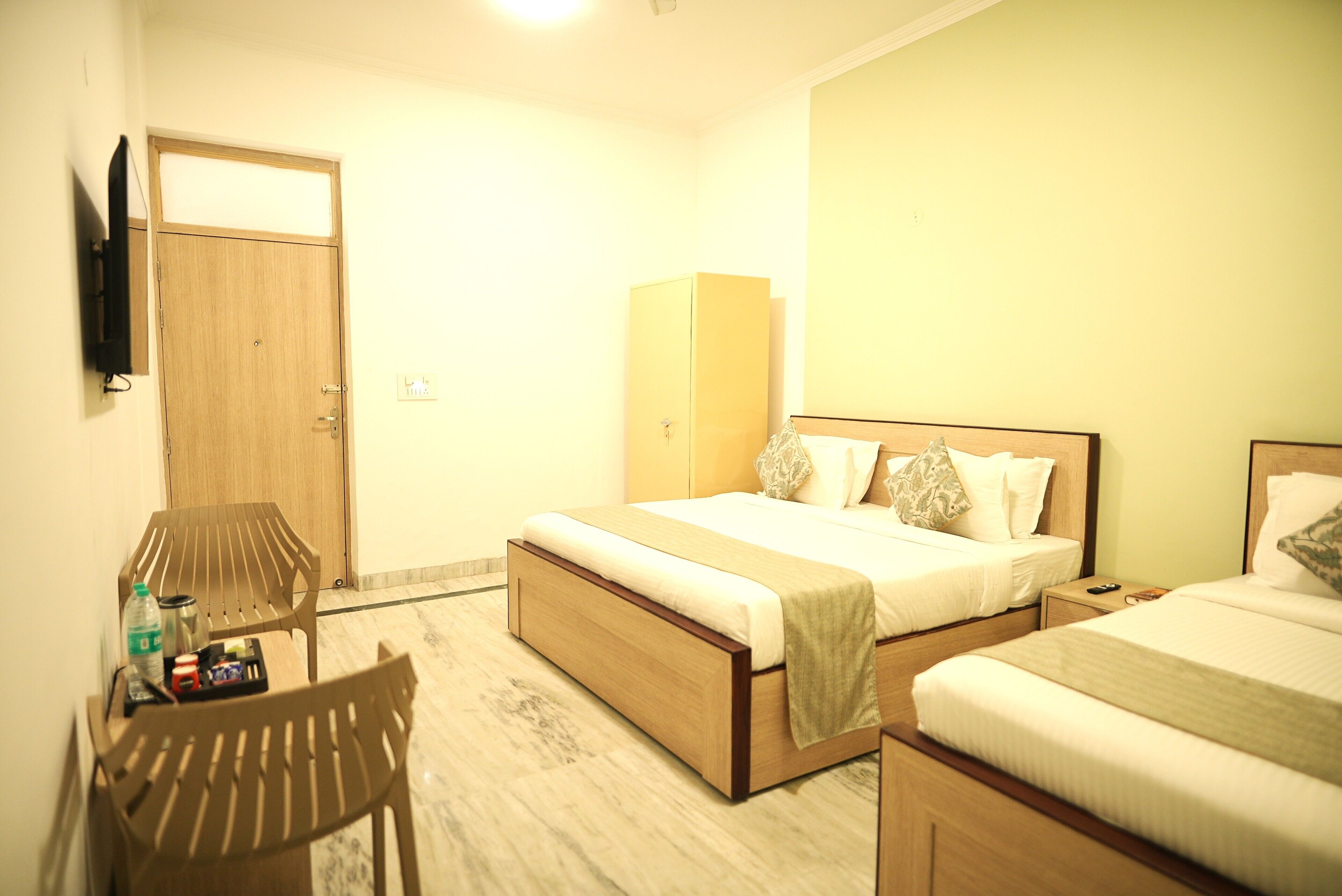 A hotel room with a bed, a desk, a chair, and a TV mounted on the wall.