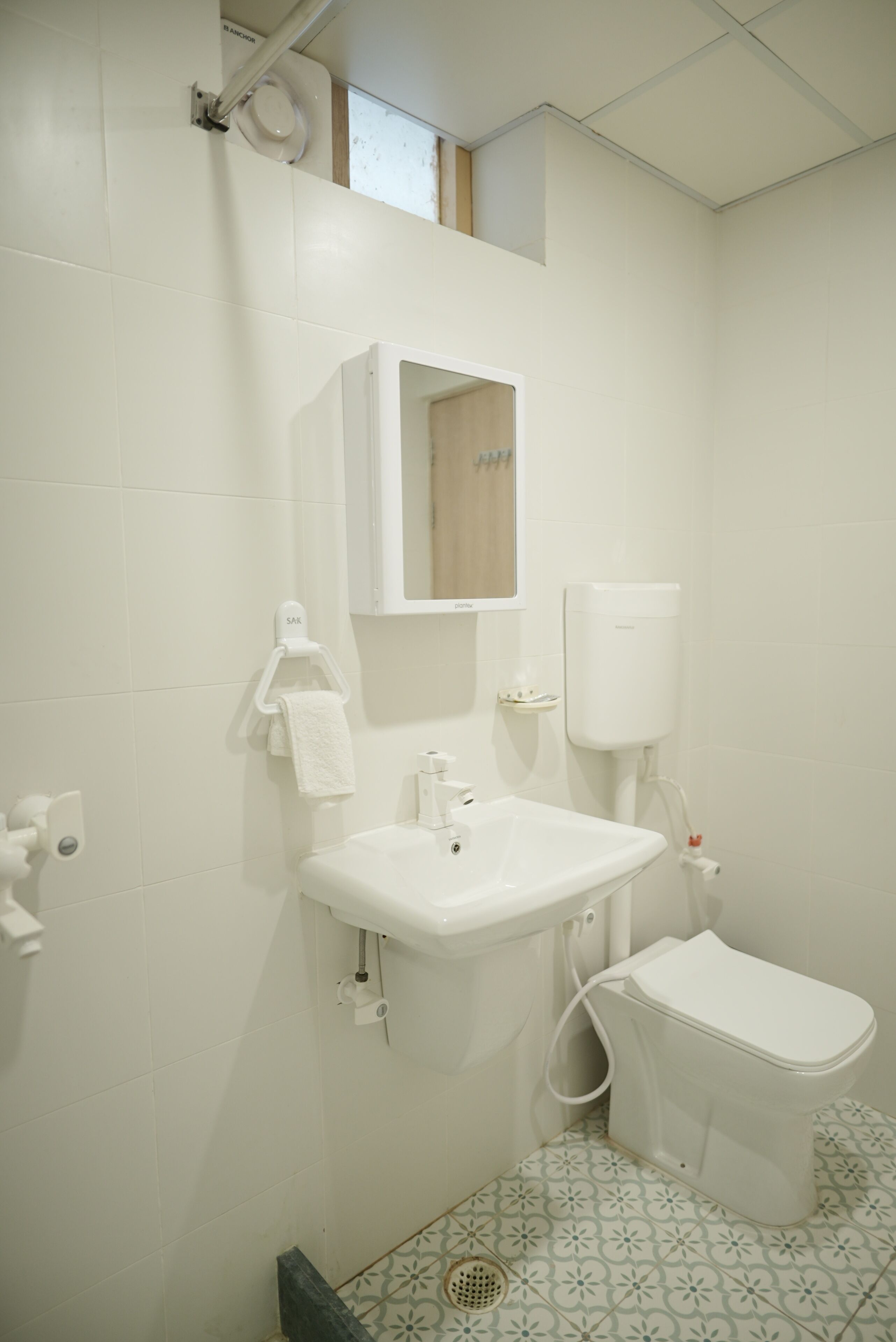 Une salle de bain avec un lavabo blanc, des toilettes et un miroir au-dessus du lavabo.