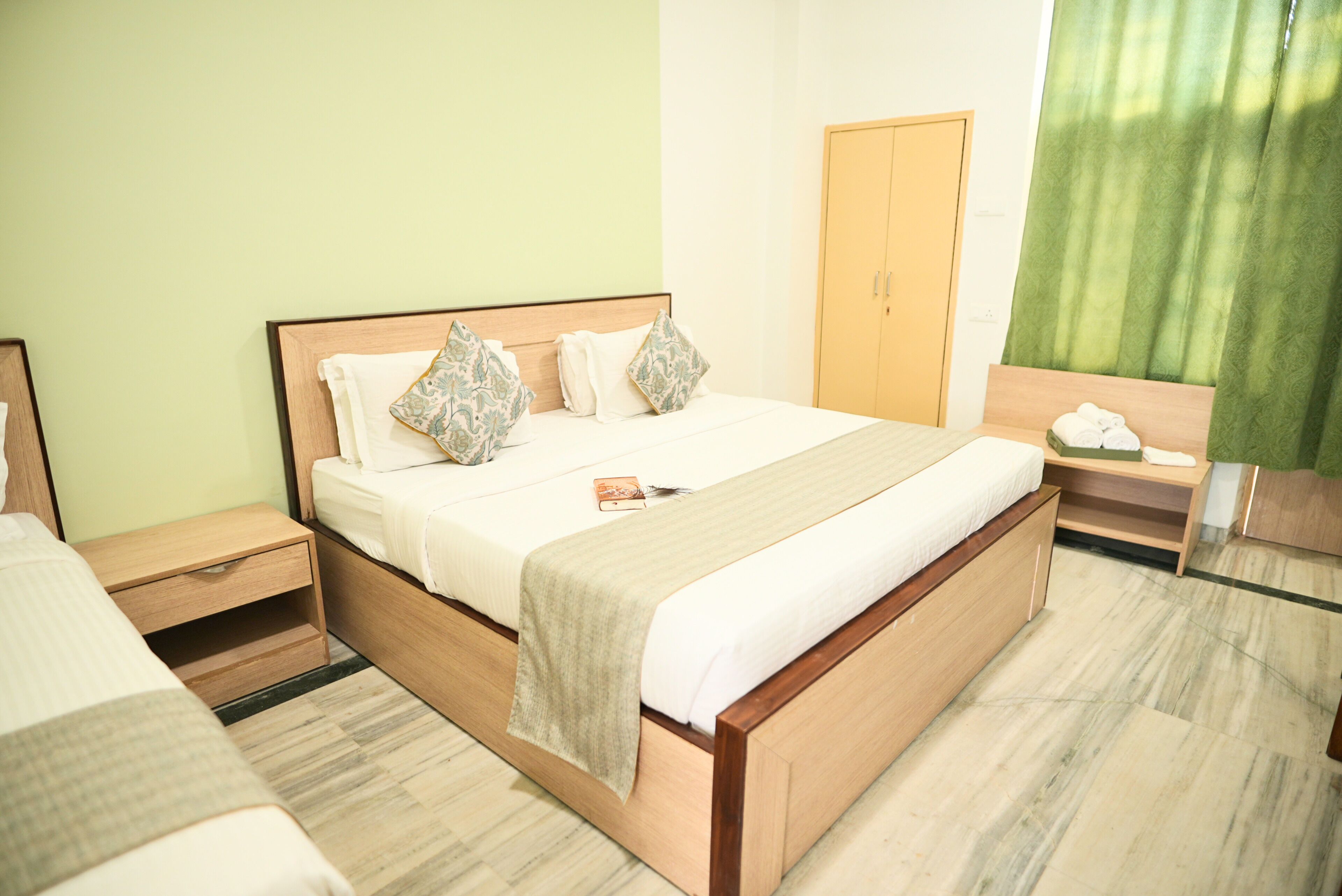 Een slaapkamer met een bed, nachtkastjes, een kledingkast en een raam met gordijnen.