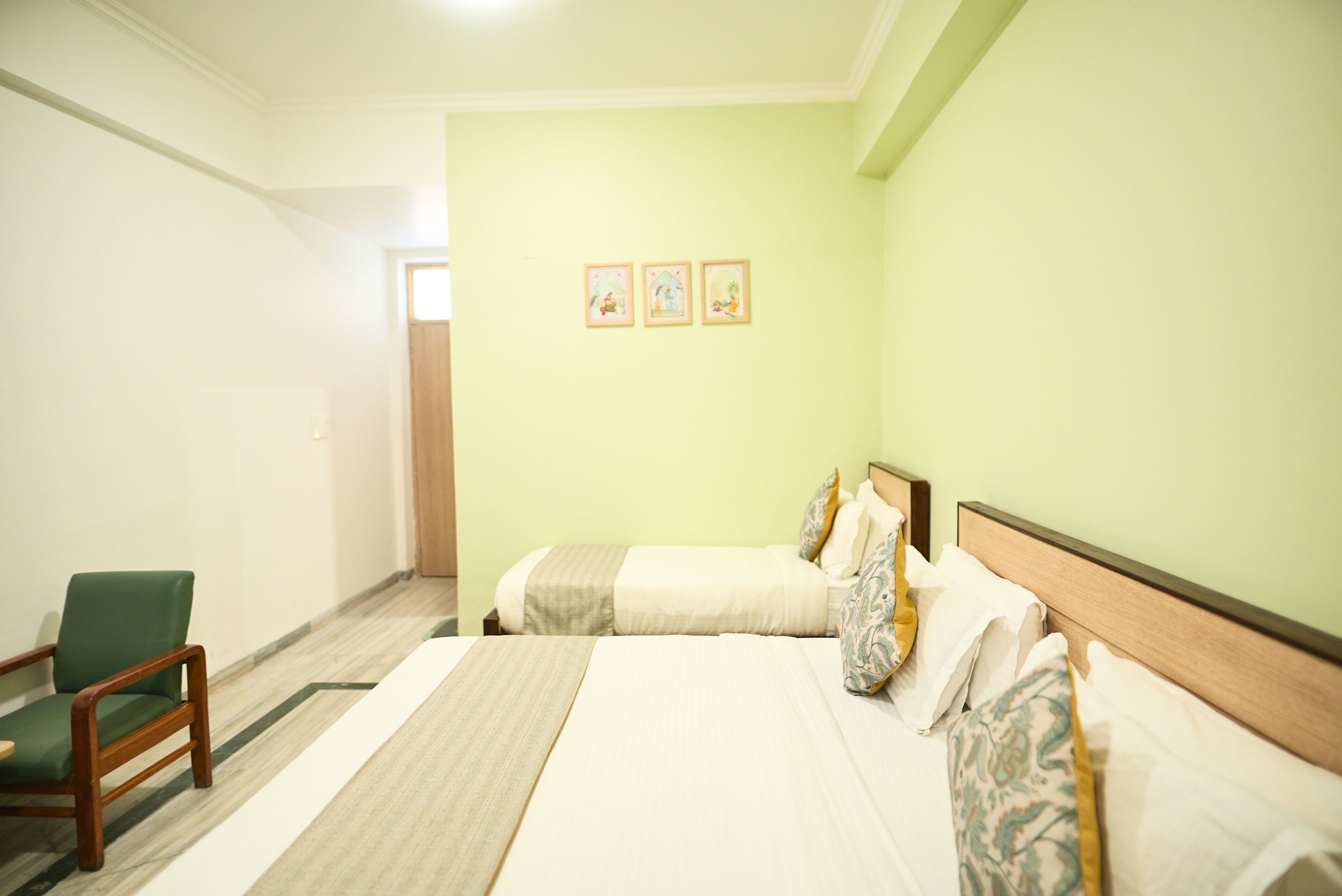 A hotel room with two beds, a chair, and a door leading to another room.