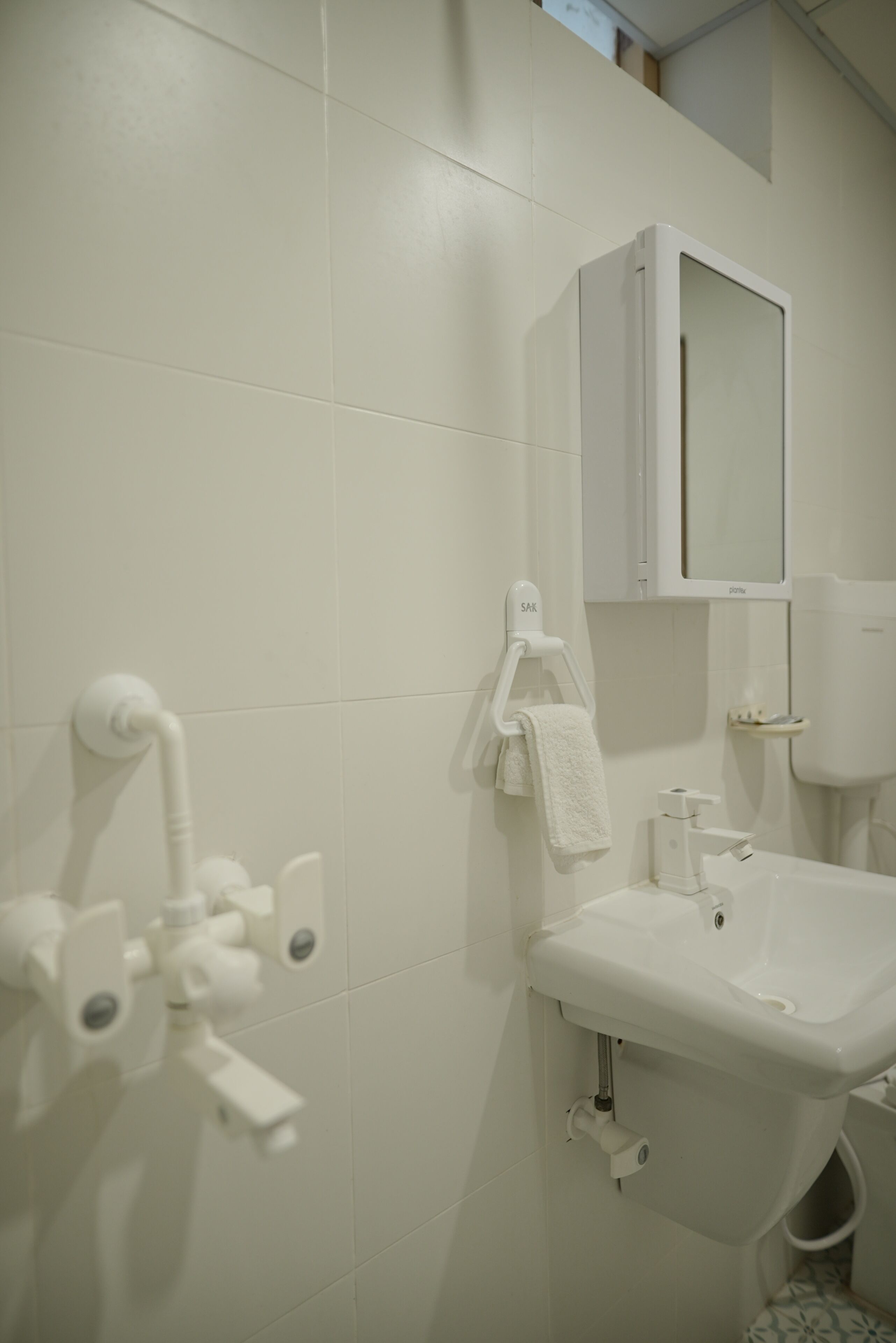 A bathroom with white tiles, a sink, a mirror, and a towel rack.