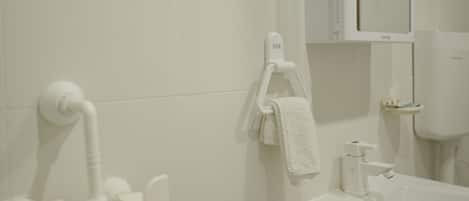 A bathroom with white tiles, a sink, a mirror, and a towel rack.