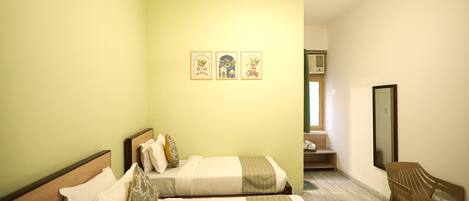 A hotel room with two beds, a chair, a small table, and a mirror.