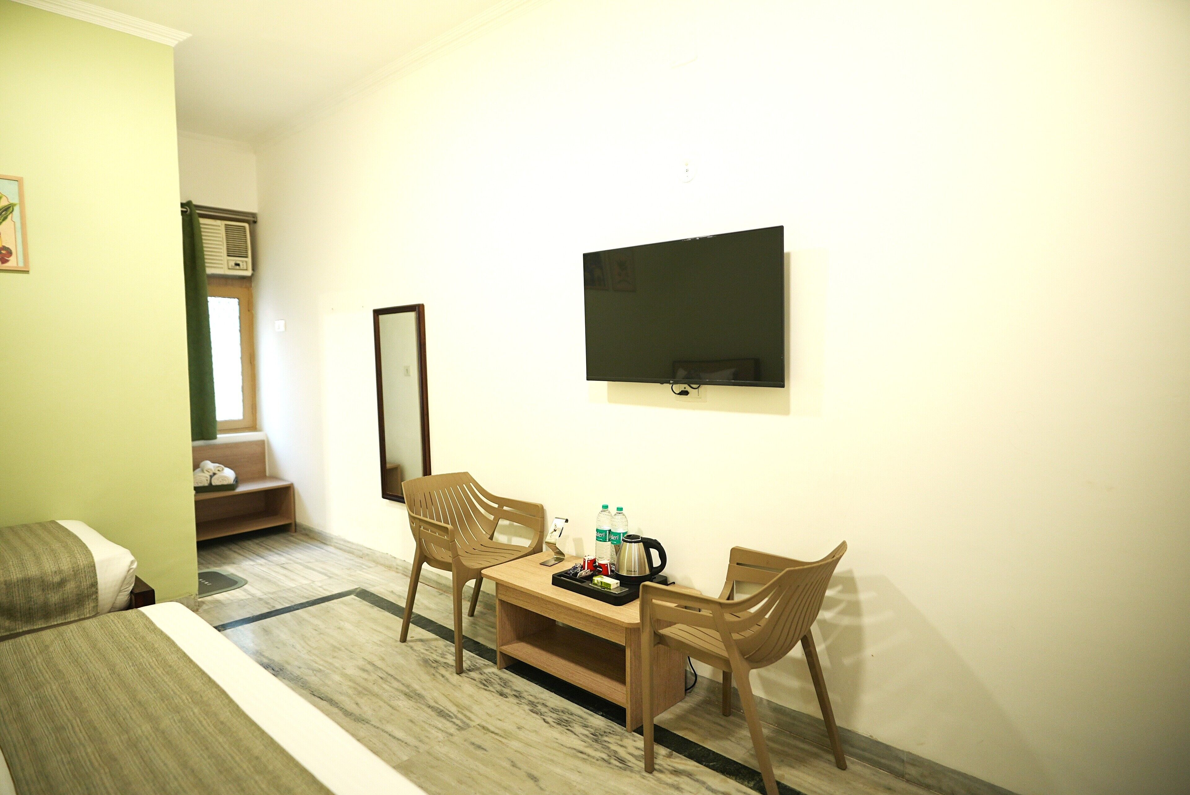 Habitación de hotel con cama, escritorio con sillas, televisor de pantalla plana y ventana con vistas.