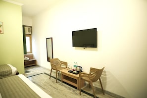 A hotel room with a bed, a desk with chairs, a flat-screen TV, and a window with a view.