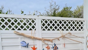 A white wooden fence with a lattice top, decorated with colorful fish and starfish ornaments. - Ferienhaus direkt am Wasser by Interhome (Stralsund)