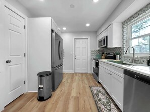 A modern kitchen with white cabinetry, stainless steel appliances, and a wooden floor. - Casa De Campo Unit A Up to 3 (Tampa)