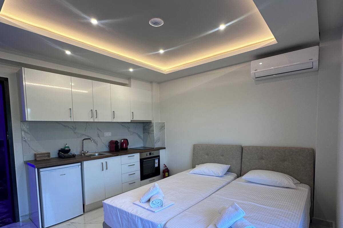 Une chambre d’hôtel moderne dotée d’un grand lit, d’une petite kitchenette et d’un plafond équipé d’un système d’éclairage encastré.