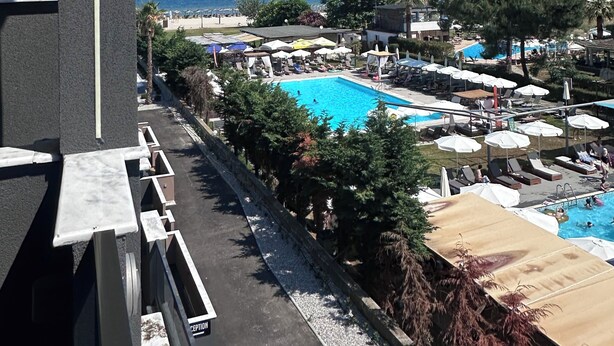 Zona de piscina con sombrillas, sillas de descanso y vista al mar.