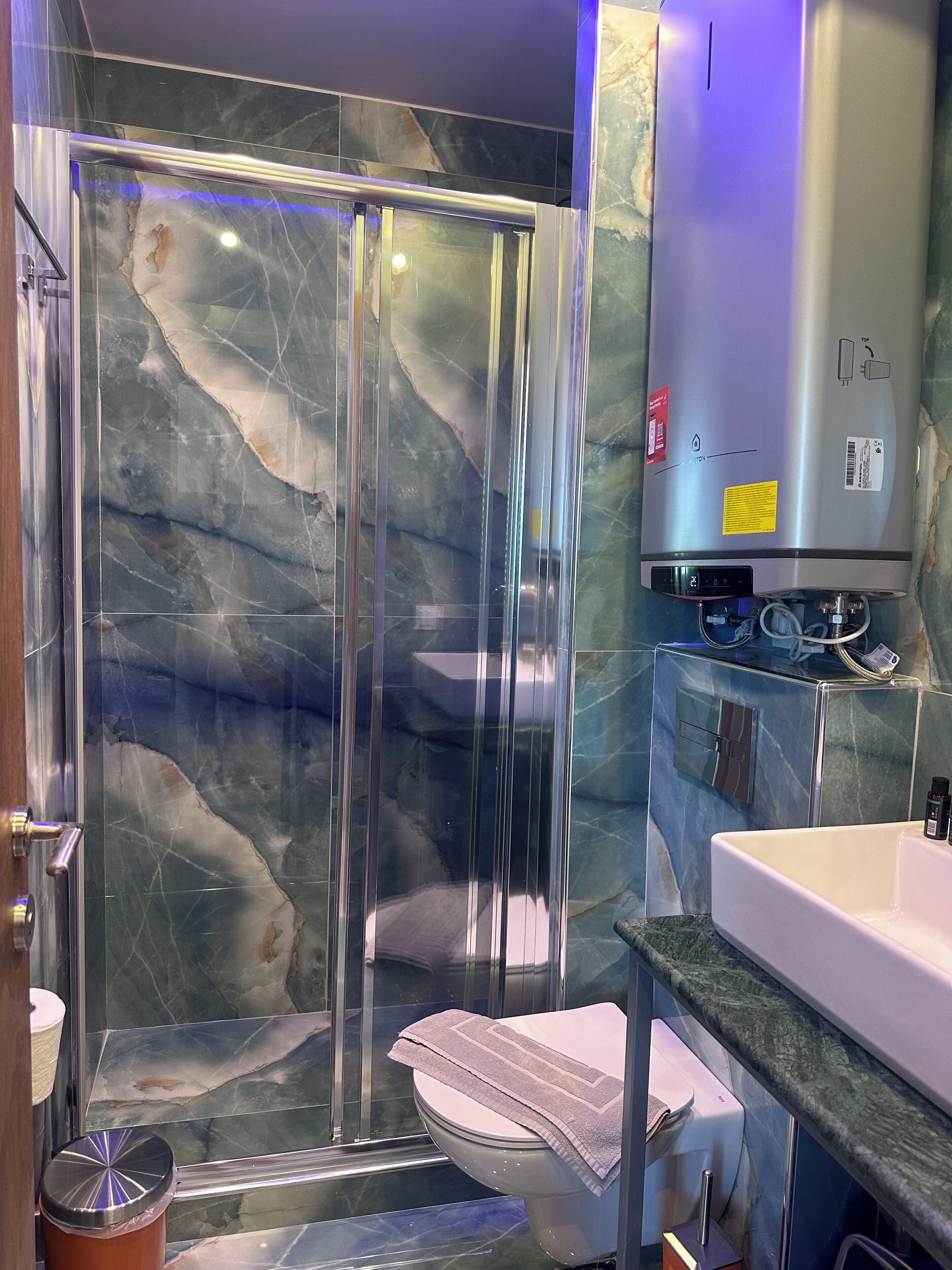 A modern bathroom with a glass-enclosed shower, a toilet, and a sink.