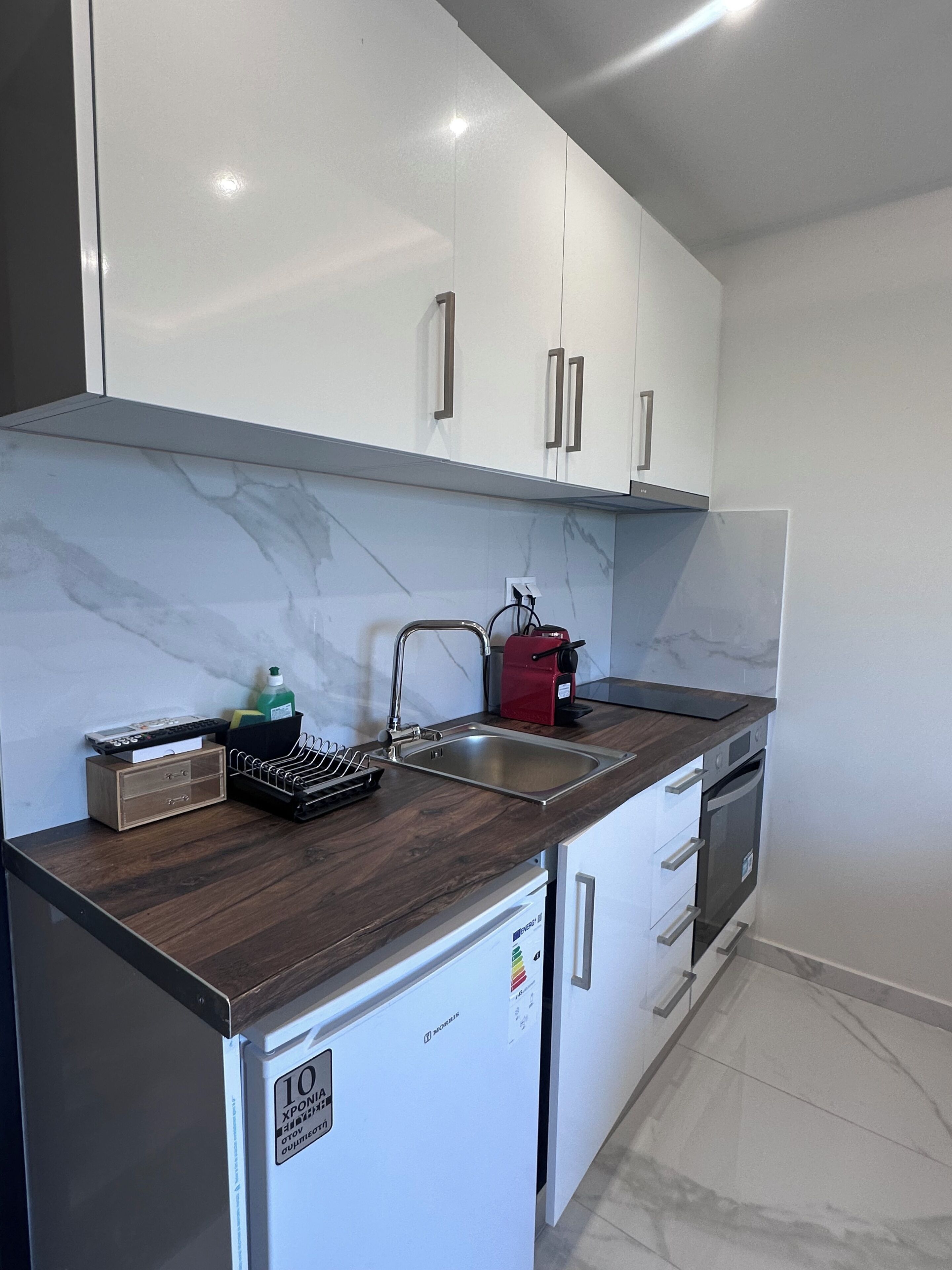 A kitchen with white cabinets, a stainless steel sink, a red appliance, and a small refrigerator.