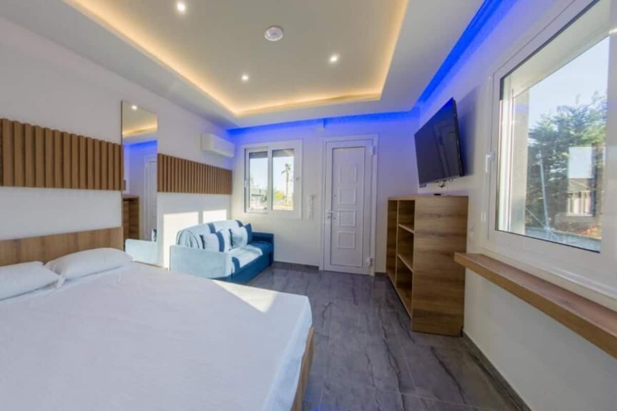 Une chambre d’hôtel moderne dotée d’un grand lit, d’un coin salon, d’une télévision et d’une fenêtre.