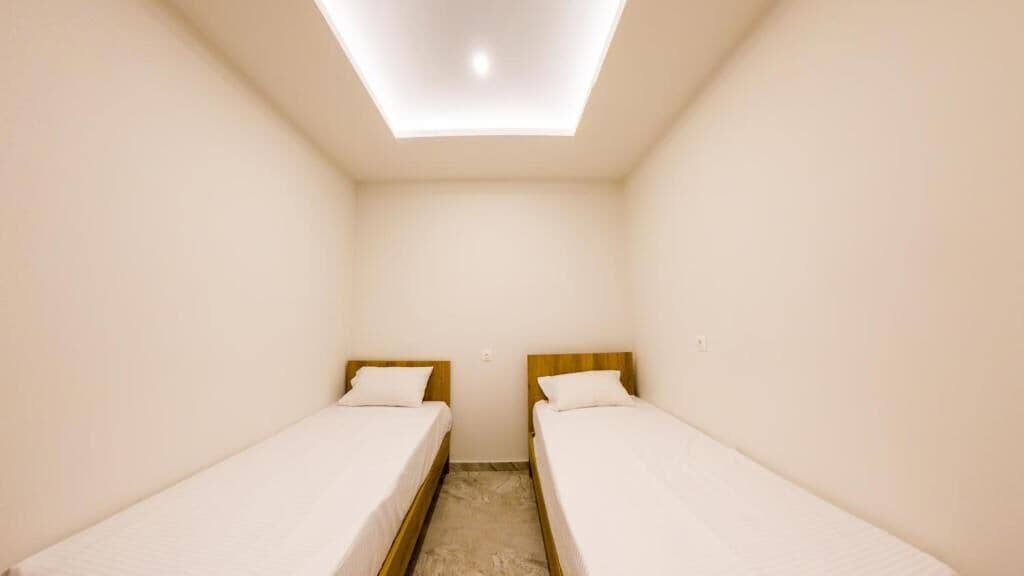 A small, clean room with two single beds and a skylight.