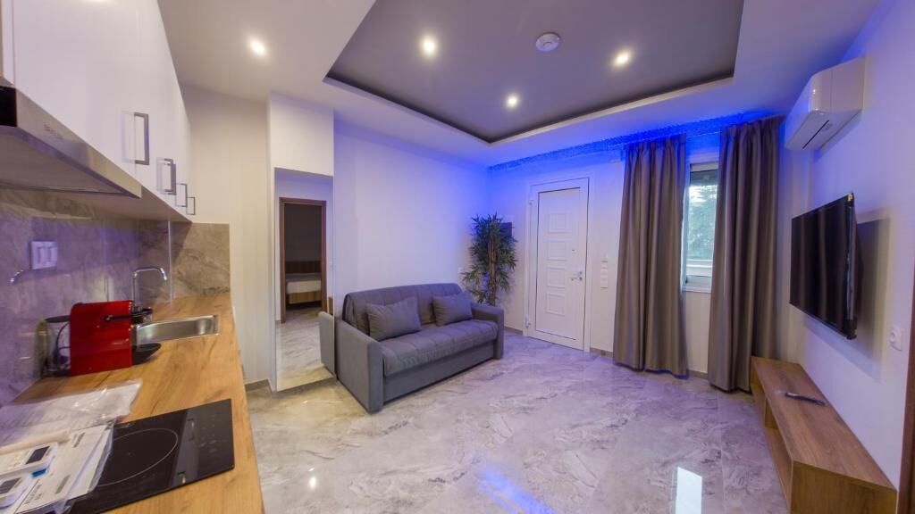Una sala de estar moderna con un sofá gris, una mesa de centro de madera y un televisor de pantalla plana montado en la pared.