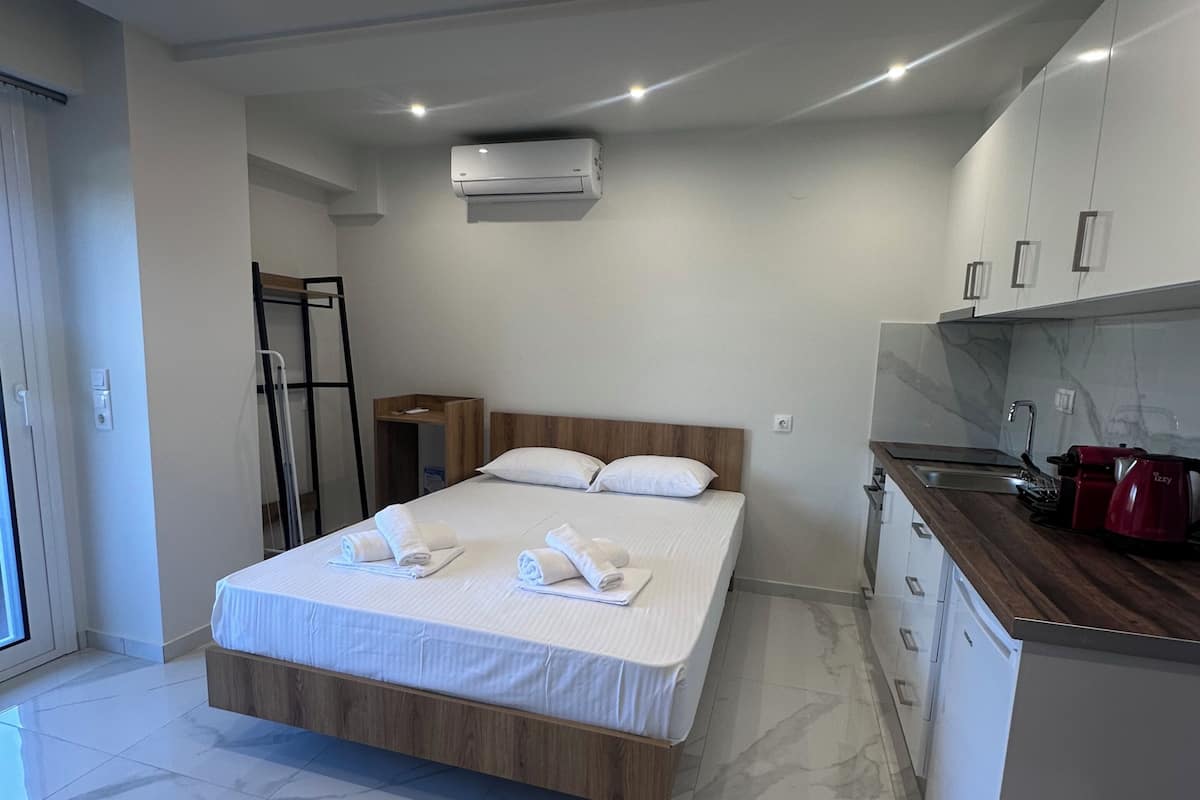 Une chambre d’hôtel moderne équipée d’un lit, d’une petite kitchenette et d’une salle de bain.