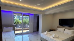 Un dormitorio moderno con una cama grande, una cama más pequeña, un televisor y un balcón con puertas de vidrio.