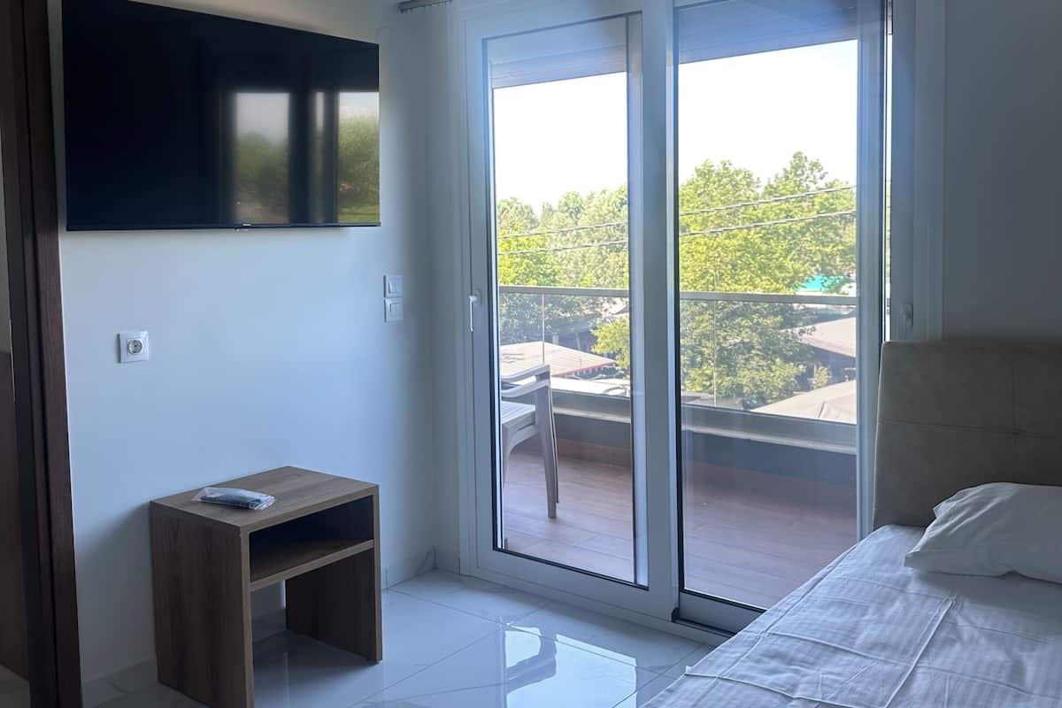 Une chambre moderne avec un lit, un téléviseur fixé au mur et un balcon offrant une vue agréable.