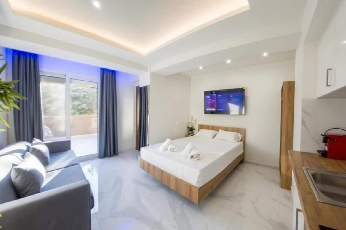 Une chambre d’hôtel moderne équipée d’un lit, d’un bureau, d’une télévision et d’un coin cuisine.