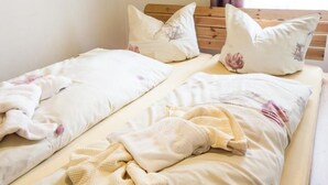 Ein Doppelbett mit Holzvorhang, zwei Kissen und einer Decke.