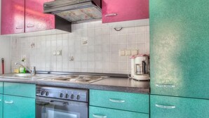 Eine Küche mit türkisfarbenen Schränken, einem Edelstahlherd und einer gefliesten Spritzschutzwand.