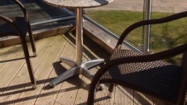 Een balkon met tafel en stoelen met uitzicht op een meer.