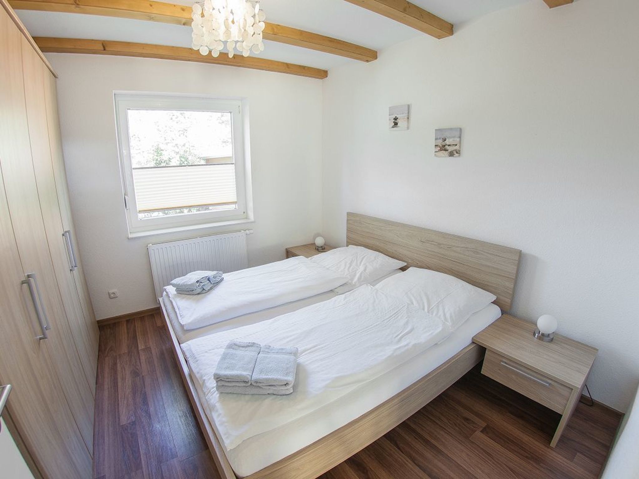 Un dormitorio con dos camas, piso de madera, una ventana y un radiador.