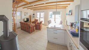 Een ruime woonkamer met een open haard, een eettafel en een keuken met moderne apparatuur.