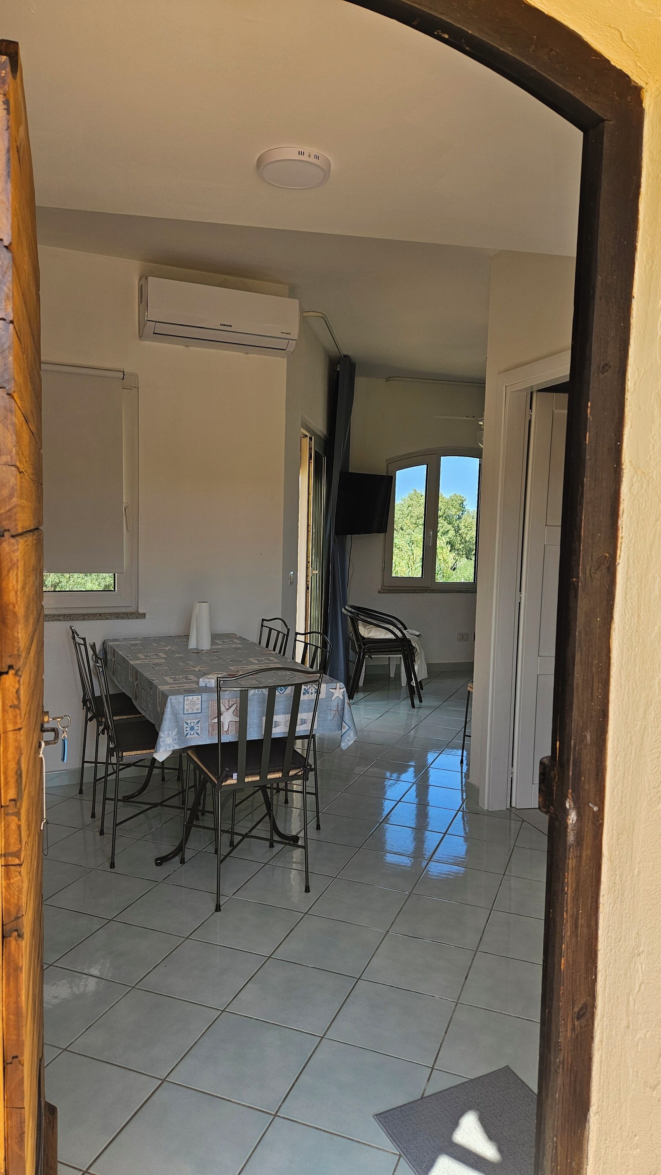 Un comedor con una mesa y sillas, un equipo de aire acondicionado y vistas al exterior a través de una ventana.