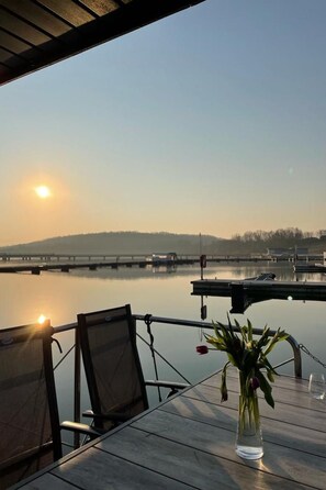 A table with a clear view of a calm body of water, a distant bridge, and a hilly landscape. - Hausboot mit Sauna by Interhome (Braunsbedra)